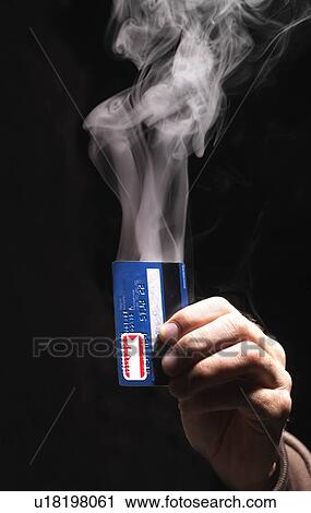 Stock Image - Hand holding smoking credit card. Fotosearch