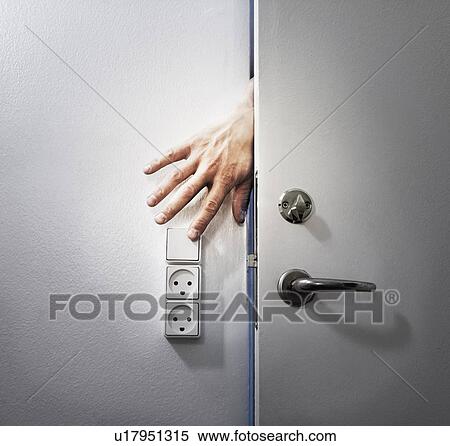 Stock Photography - Hand turning off light from behind door. Fotosearch