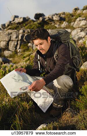 Hiker reading map in rocky field View Large Photo Image Stock Photo - Hiker reading map in rocky field. Fotosearch