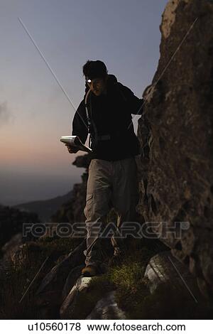 Hiker reading map on steep rock face View Large Photo Image Stock Photo - Hiker reading map on steep rock face. Fotosearch