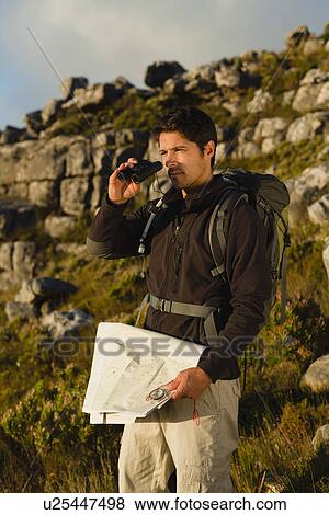 Hiker using binoculars in rocky field View Large Photo Image Stock Photo - Hiker using binoculars in rocky field. Fotosearch