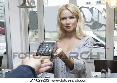 Stock Image - Hostess offering credit card machine. Fotosearch