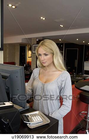 Stock Image - Hostess using computer in restaurant. Fotosearch