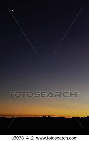 Stock Image - Illuminated moon in sunset sky. Fotosearch