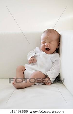 Stock Photo - Infant yawning on sofa. Fotosearch