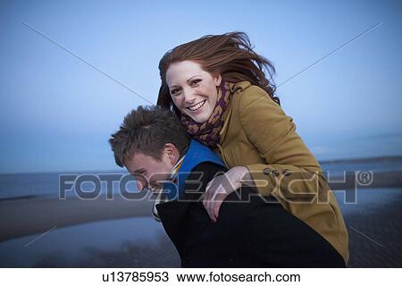 Stock Image - Man carrying girlfriend piggyback. Fotosearch