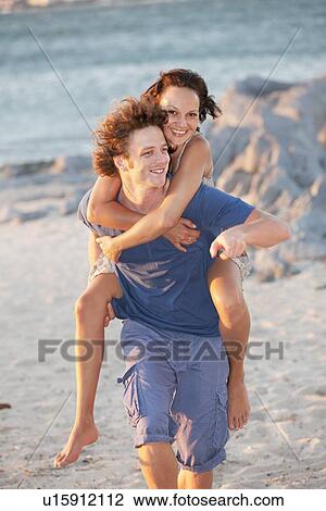 Stock Image - Man carrying girlfriend piggyback. Fotosearch