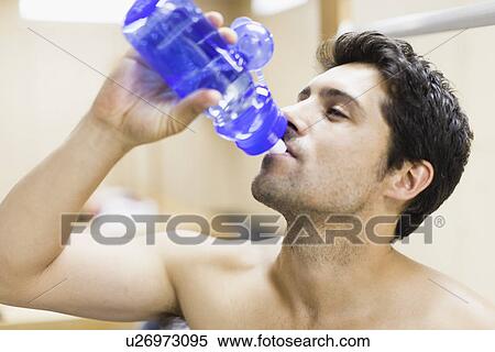 Stock Photography - Man drinking water in locker room. Fotosearch