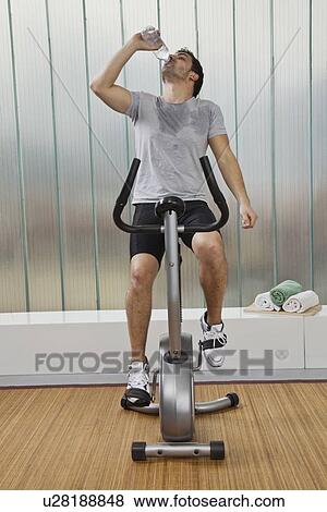 Man drinking water on exercise machine View Large Photo Image Stock Photo - Man drinking water on exercise machine. Fotosearch
