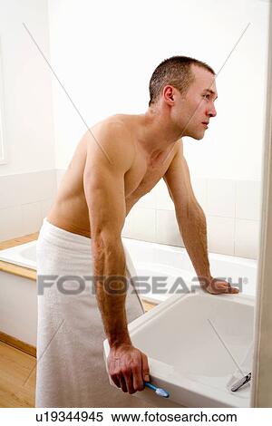Stock Photography - Man examining himself in mirror. Fotosearch