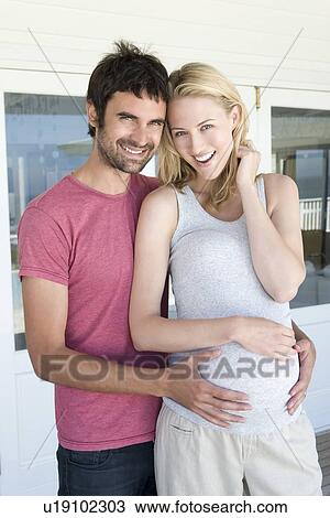 Stock Image - Man holding pregnant girlfriends belly. Fotosearch