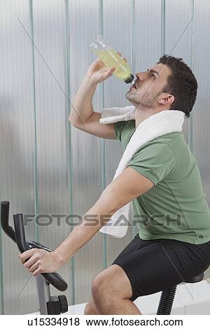 Man hydrating on exercise machine View Large Photo Image Stock Photo - Man hydrating on exercise machine. Fotosearch