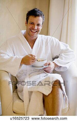 Stock Image - Man in bathrobe having bowl of cereal. Fotosearch