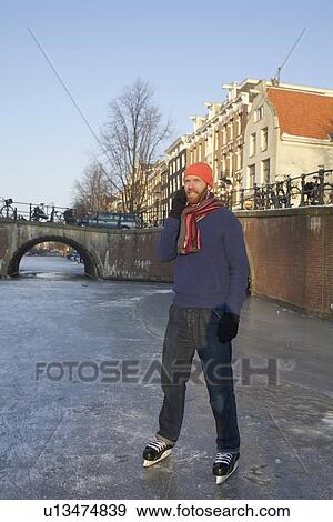 Stock Photo - Man in ice skates talking on cell phone. Fotosearch