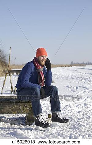 Stock Photo - Man in ice skates talking on cell phone. Fotosearch