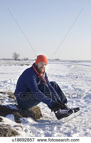 Man lacing up ice skates in snowy field View Large Photo Image Stock Photo - Man lacing up ice skates in snowy field. Fotosearch