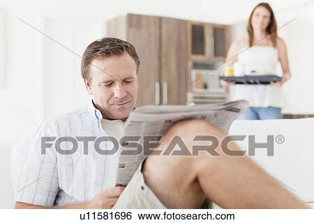 Man reading newspaper on sofa View Large Photo Image Stock Photograph - Man reading newspaper on sofa. Fotosearch