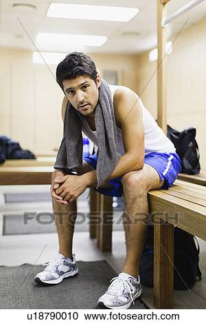 Stock Image - Man resting on locker room bench. Fotosearch