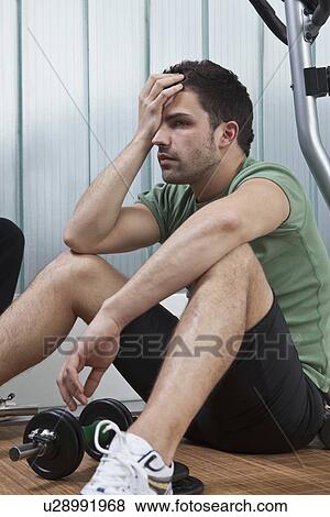 Man sitting on floor in home gym View Large Photo Image Stock Photo - Man sitting on floor in home gym. Fotosearch