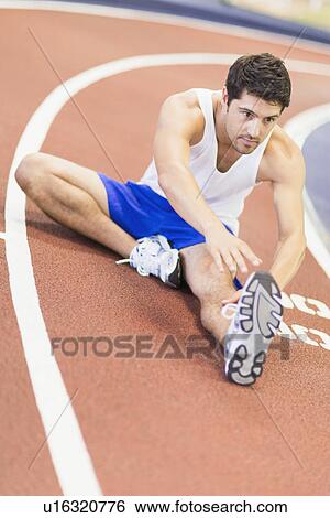 Man stretching on indoor track in gym View Large Photo Image Stock Photograph - Man stretching on indoor track in gym. Fotosearch