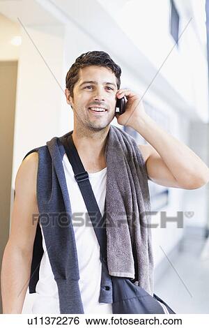 Stock Photograph - Man talking on cell phone in locker room. Fotosearch