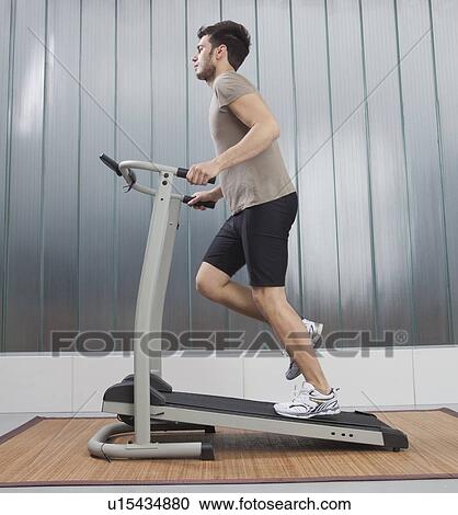 Stock Image - Man using exercise machine. Fotosearch