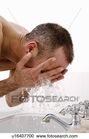 Stock Image - Man washing his face in bathroom. Fotosearch