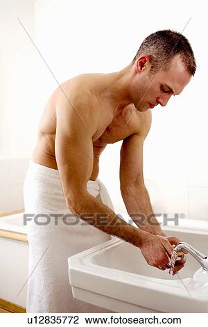 Stock Image - Man washing his hands in bathroom. Fotosearch
