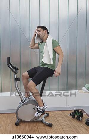 Man wiping sweat on exercise machine View Large Photo Image Picture - Man wiping sweat on exercise machine. Fotosearch