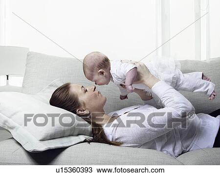 Mother and baby relaxing on sofa View Large Photo Image Stock Image - Mother and baby relaxing on sofa. Fotosearch