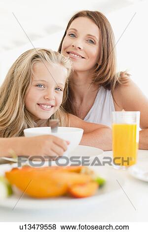 Stock Photo - Mother and daughter at breakfast table. Fotosearch