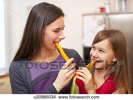 Mother and daughter eating carrots View Large Photo Image Picture - Mother and daughter eating carrots. Fotosearch