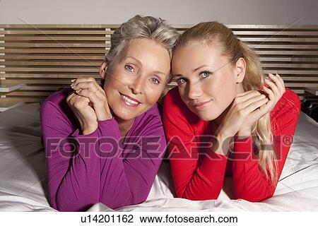 Mother and daughter laying on bed View Large Photo Image Stock Image - Mother and daughter laying on bed. Fotosearch
