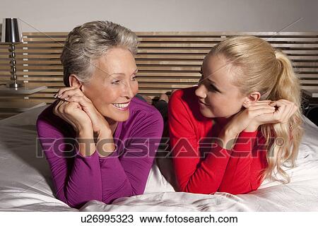 Mother and daughter laying on bed View Large Photo Image Stock Image - Mother and daughter laying on bed. Fotosearch