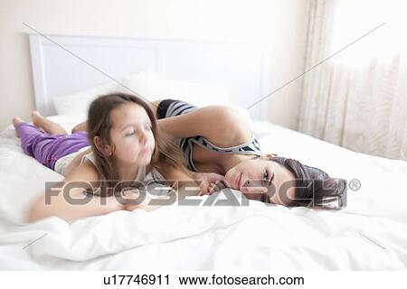 Mother and daughter relaxing in bed View Large Photo Image Stock Image - Mother and daughter relaxing in bed. Fotosearch