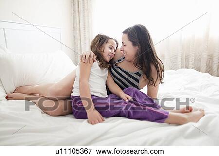 Stock Photo - Mother and daughter relaxing in bed. Fotosearch