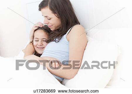 Mother and daughter relaxing in bed View Large Photo Image Stock Photo - Mother and daughter relaxing in bed. Fotosearch