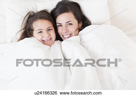 Stock Photograph - Mother and daughter relaxing in bed. Fotosearch