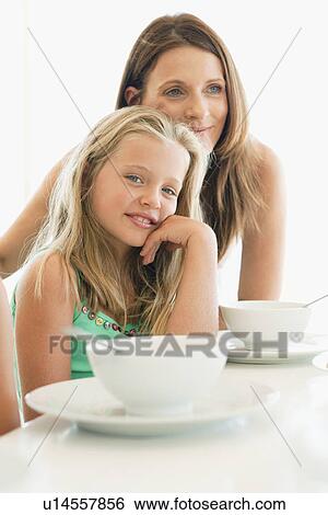 Stock Photograph - Mother and daughter sitting at table. Fotosearch