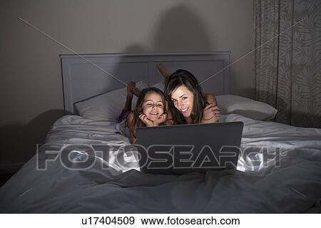 Stock Photo - Mother and daughter using laptop in bed. Fotosearch