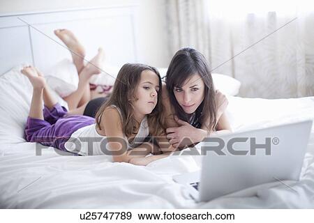 Mother and daughter using laptop in bed View Large Photo Image Stock Photo - Mother and daughter using laptop in bed. Fotosearch