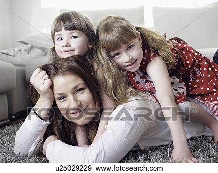 Stock Photo - Mother and daughters laying on rug. Fotosearch