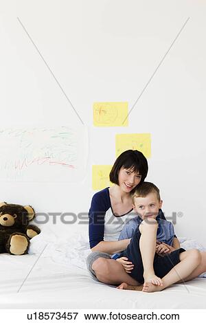 Stock Photo - Mother and son sitting on bed. Fotosearch
