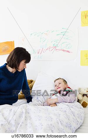 Stock Image - Mother checking on sick son. Fotosearch