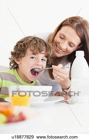 Stock Photo - Mother feeding son cereal. Fotosearch