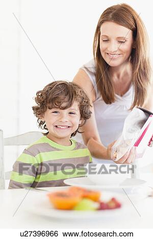 Mother pouring cereal for son View Large Photo Image Stock Photograph - Mother pouring cereal for son. Fotosearch