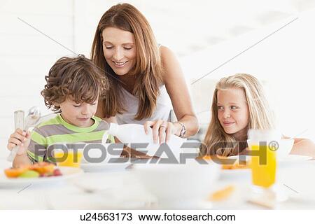 Stock Image - Mother pouring milk for son. Fotosearch