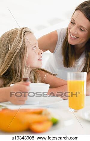 Stock Photo - Mother talking to daughter at breakfast. Fotosearch