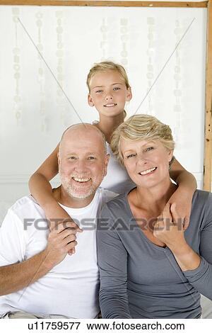 Stock Photo - Older couple hugging granddaughter. Fotosearch