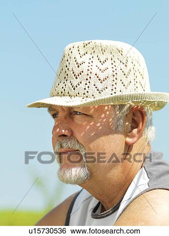 Stock Photograph - Older man wearing straw hat outdoors. Fotosearch